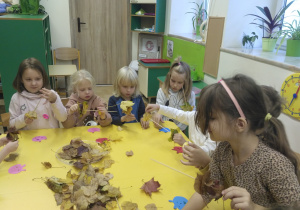 Dzieci wykonują pracę plastyczną z liści