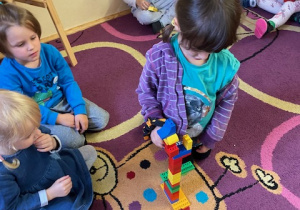 Dzieci budują wieżowiec z klocków Lego