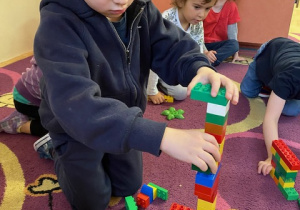 Dzieci budują wieżowiec z klocków Lego