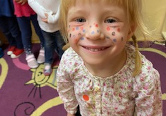 Uśmiechnięta dziewczynka z namalowanymi piegami na twarzy w wybranych przez Nią kolorach
