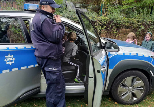 Dzieci i policjant przy radiowozie